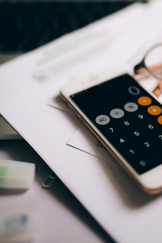 Phone calculator app on top of paperwork with reading glasses representing the cost breakdown for California small claims