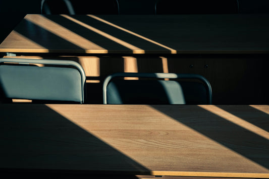 Empty courtroom-style table and chair in hard window light, the scene when a defendant fails to appear and a default