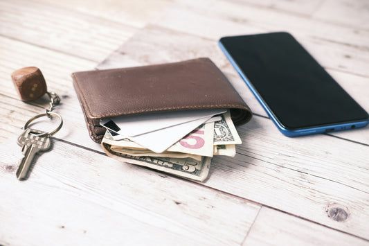 Brown wallet stuffed with cash beside house keys and a phone representing collecting money on a California small claims