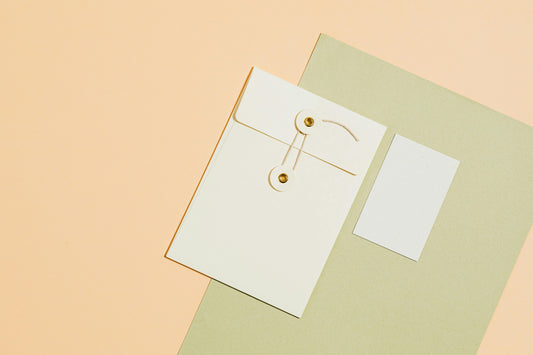 White string-and-button envelope on a peach and sage background, representing how to serve small claims papers in California