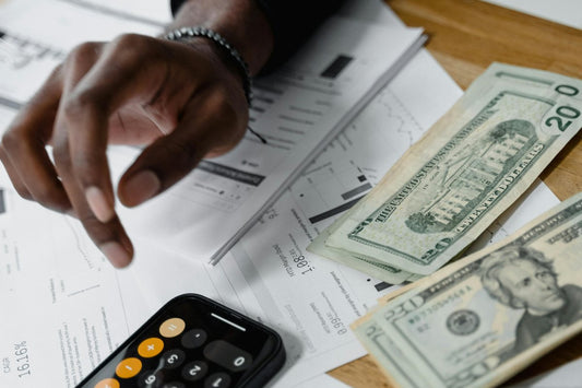 Person at a desk with a calculator, twenty-dollar bills, and financial paperwork weighing whether small claims court is